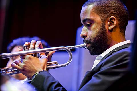 Man in a dark suit playing a trumpet