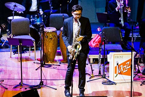 Man on stage performing a solo with a saxophone