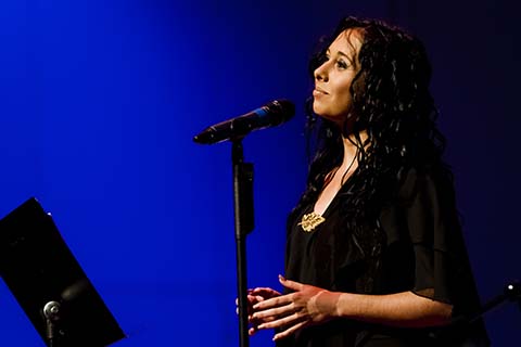 Solo vocalists in a black dress pauses during a performance on stage