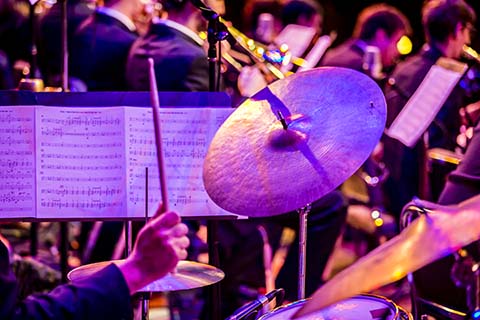 A cymbal fro ma drum set about to get hit by an incoming drumstick