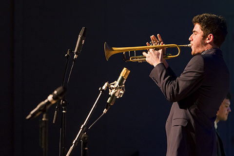 Trumpet player in a black suit performs a solo during an event